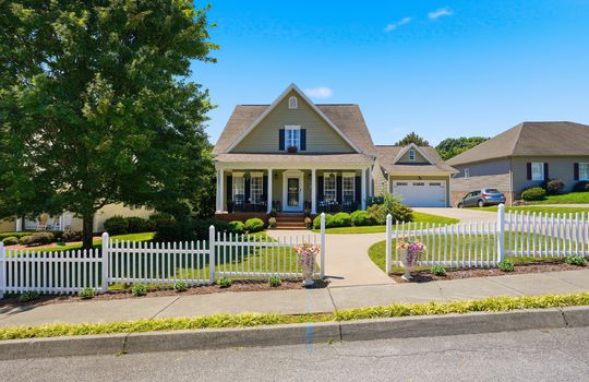street view of home, traditional style home, fence, sidewalk, landscaping, front porch, covered front porch, vinyl siding, shingle roof, garage