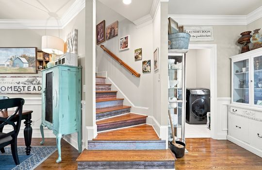 stairs to upper level, door to laundry space, hardwood flooring