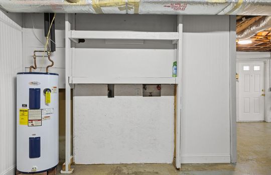 utility space in garage, washer/dryer hookups, water heater, exterior door, concrete flooring