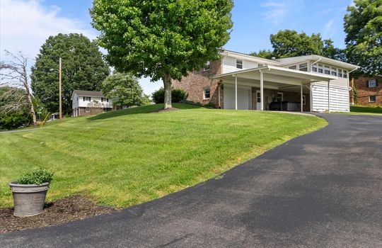 driveway, carport, garage, garage door, patio, sunroom, brick exterior, yard, trees, neighboring homes