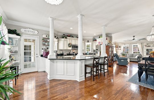 Kitchen, island, granite countertops, cabinets, stainless appliances, hardwood flooring, open to dining space and living room