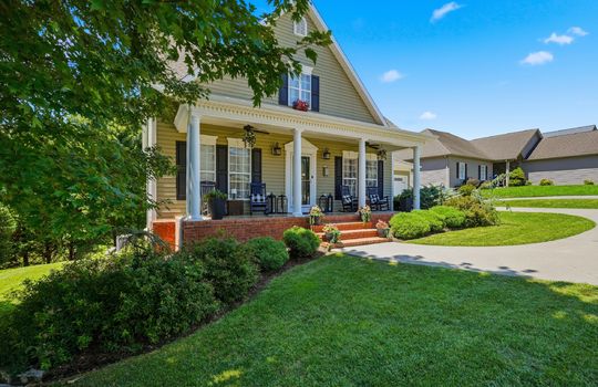 driveway view of home, traditional home, vinyl siding, two car garage, shingle roof, covered front porch, sidewalk, front door, landscaping