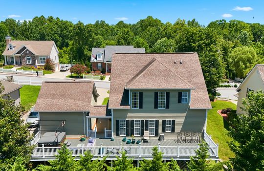 aerial view of back of home, back deck, railing, vinyl siding, shingle roof, exterior doors, breezeway, garage, trees, neighboring homes