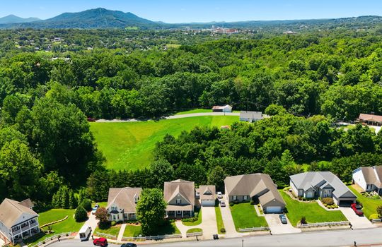 aerial view of home, front of home, sidewalk, driveway, concrete driveway, garage, 2 car garage, shingle roof, neighboring homes, mountains