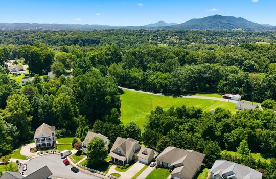 aerial view of home, front of home, sidewalk, driveway, concrete driveway, garage, 2 car garage, shingle roof, neighboring homes, mountains