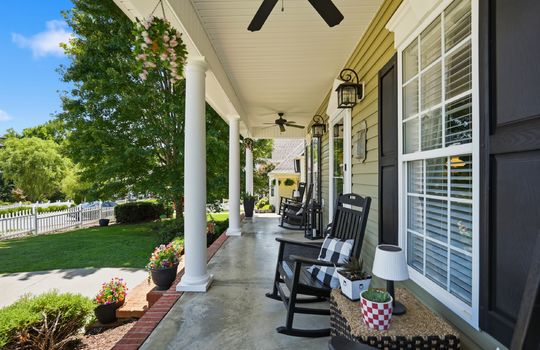 covered front porch, concrete porch, brick, vinyl siding, outdoor ceiling fans, front door, storm door