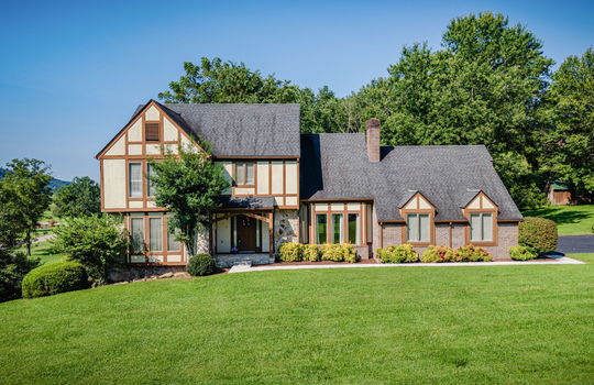 Tudor Style Home, Brick, Wood Siding, Shingle Roof, Front yard, sidewalk, covered front porch, front door, landscaping, driveway
