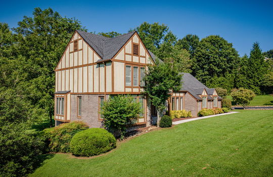 Left Side view of home, Tudor style home, brick, wood siding, landscaping, front yard, sidewalk, driveway, trees