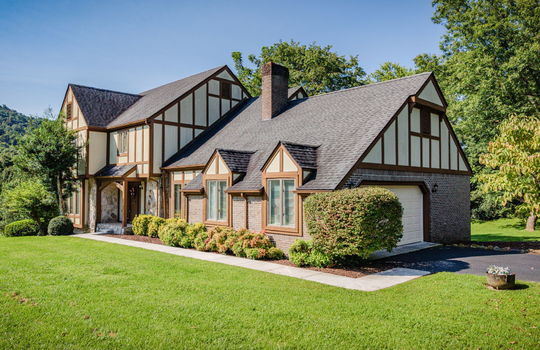 right side view of home, Tudor style home, garage, driveway, sidewalk, landscaping, front door, covered front porch, Tudor style home, windows, brick, wood siding