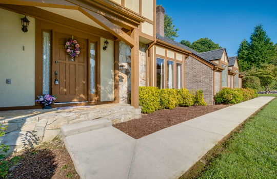 sidwalk, covered front porch, windows, tudor style home, brick, wood siding, front door, landscaping