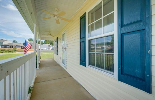 covered front porch, concrete, storm door, ceiling fans, windows, front door, vinyl siding