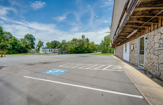 covered entry, parking lot, parking spaces, stone exterior
