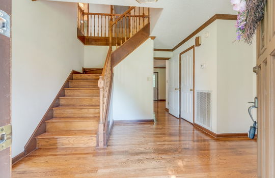 foyer, hardwood flooring, wood stairs, closet, front door