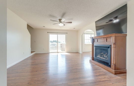 living room, luxury vinyl flooring, ceiling fan, sliding glass door, arched doorway