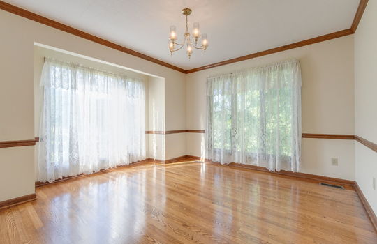 dining space, hardwood flooring, chandelier, windows, wood trim