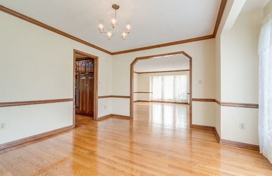 dining space, door to living room, door to kitchen, chandelier, wood trim, hardwood flooring