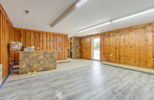 additional open area, checkout counter, vinyl flooring, wood paneling walls, fluorescent lighting, glass entry door