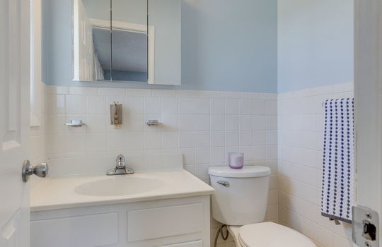 ensuite half bath, tile flooring, tile walls, sink, toilet