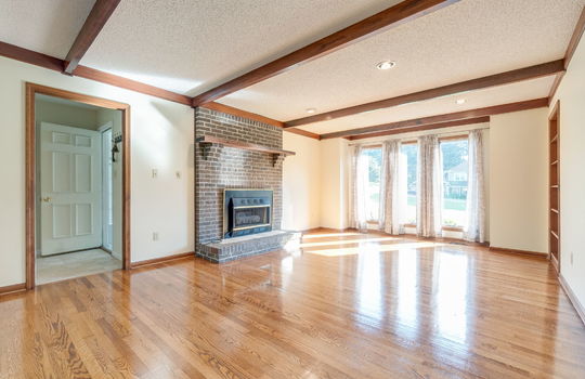Family room, hardwood flooring, built-in shelving, fireplace, wood beam features on ceiling, recessed lighting, windows
