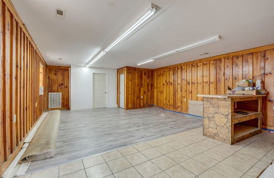 additional open area, checkout counter, vinyl flooring, wood paneling walls, fluorescent lighting, glass entry door