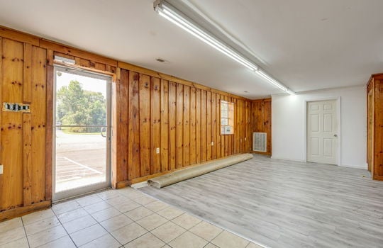 additional open area, checkout counter, vinyl flooring, wood paneling walls, fluorescent lighting, glass entry door