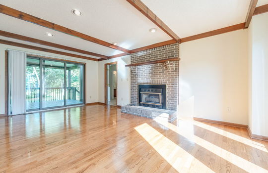 family room, sliding glass door, brick fireplace, wood ceiling beams, hardwood flooring