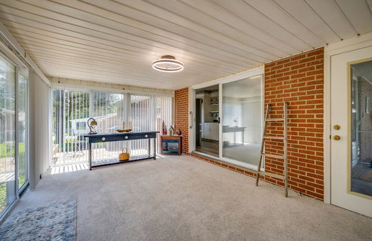 heated sunroom, carpet, windows, sliding glass door to interior