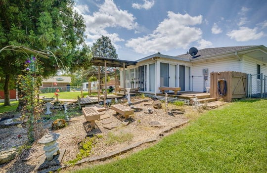 back of home, landscaping, doors to heated sunroom, back yard