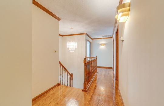 second floor landing/hallway, hardwood flooring, railing, stairs, chandelier, wall sconces