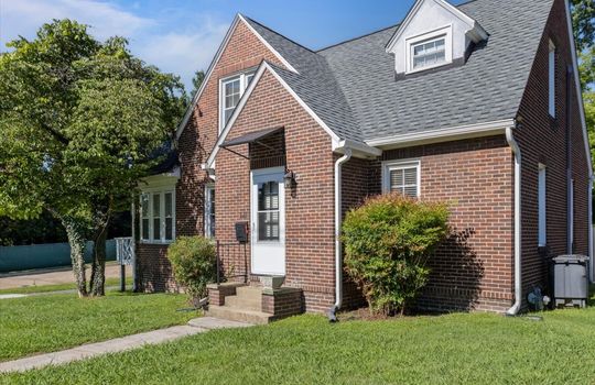 right side view of home, shingle roof, exterior brick, front door, steps, sidewalk, front yard