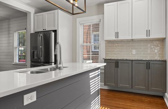 Kitchen, island, island in sink, tile backsplash, shaker cabinets, windows, stainless appliances, hardwood flooring