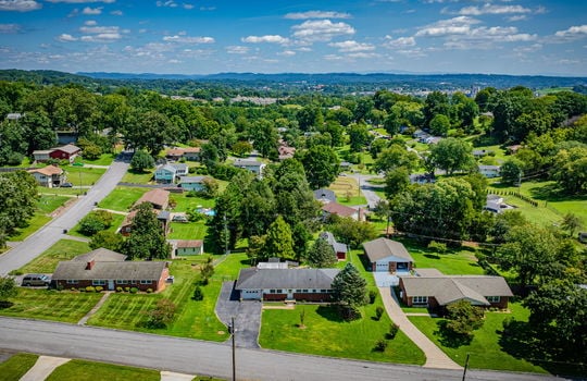 aerial view of home, front yard, driveway, single roof, garage, brick ranch home, neighboring homes, road, mountains