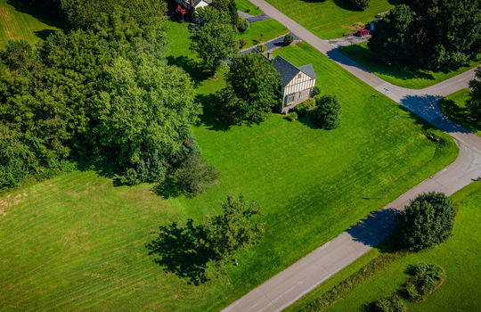 side view of home, aerial view of home, tudor style home, back yard, gront yard, trees, road