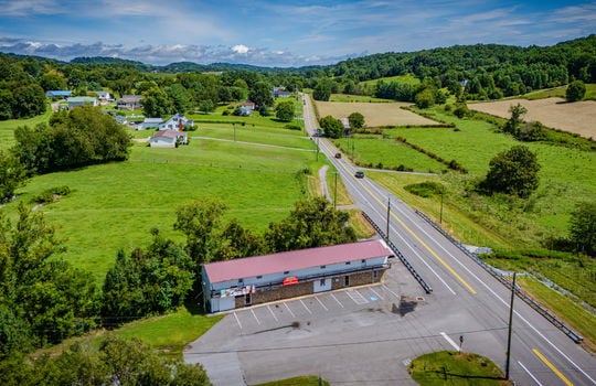 overhead aerial view of property, commercial space for lease, road, parking lot, parking spaces, metal roof, stone exterior, nearby properties, mountain views