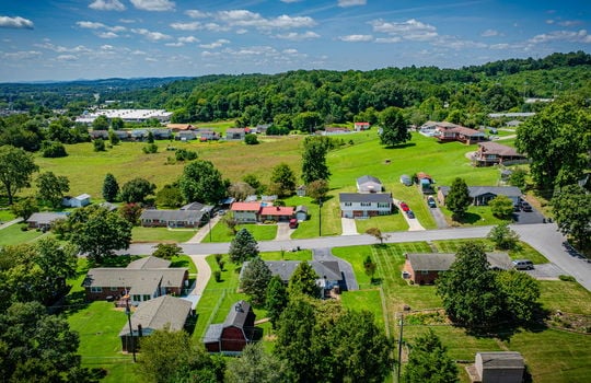 aerial view of home, front yard, driveway, single roof, garage, brick ranch home, neighboring homes, road, mountains
