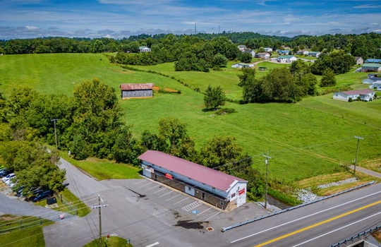 overhead aerial view of property, commercial space for lease, road, parking lot, parking spaces, metal roof, stone exterior, nearby properties, mountain views