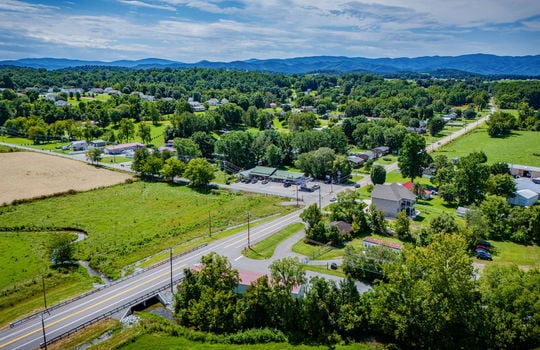 overhead aerial view of property, commercial space for lease, road, parking lot, parking spaces, metal roof, stone exterior, nearby properties, mountain views