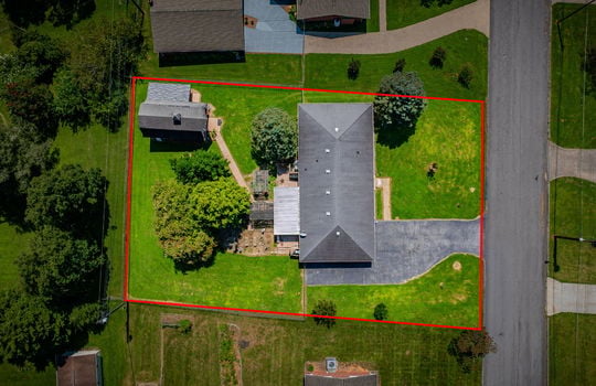 overhead aerial view of home, front yard, trees, landscaping, road, driveway, roof, shingle roof, back yard, landscaping, storage shed/outbuilding, fenced back yard, property outline
