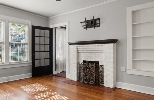 living room, built-in shelving, hardwood flooring, brick fireplace, glass door