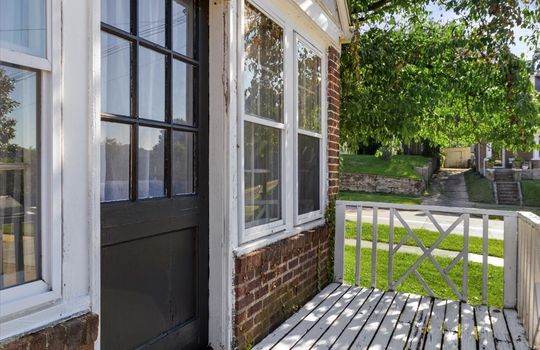 side porch, brick exterior, windows, view toward front yard