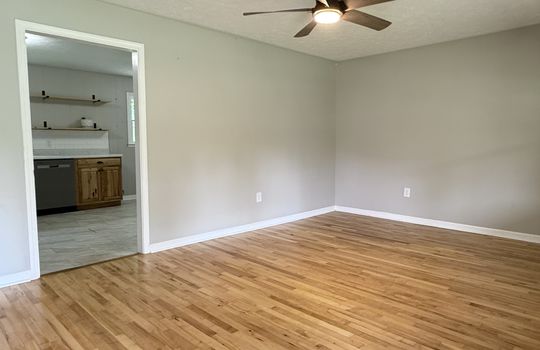 living room, hardwood flooring, ceiling fan, doorway to kitchen