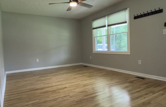 living room, ceiling fan, front door, windows, hardwood flooring