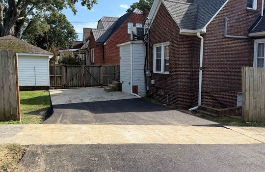 new asphalt driveway, sidewalk, back of home, fencing
