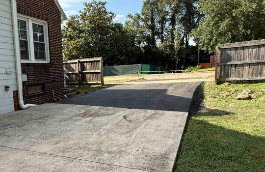 new asphalt driveway, sidewalk, fencing, back of home, back yard
