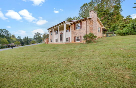right side view of home, split level home, brick, covered front porch, front door, front yard, side yard, driveway, trees