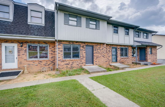 left side view of townhouse, sidewalk, stoop, brick exterior, wood siding exterior, front door, windows