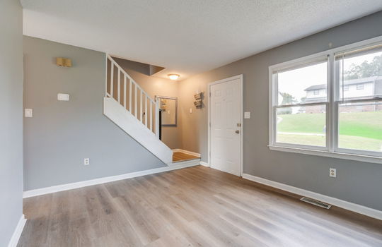 living room, front door, window, vinyl flooring, stairs to upper level