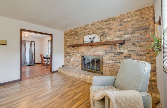 brick fireplace, living room, hardwood flooring, doorway to dining space