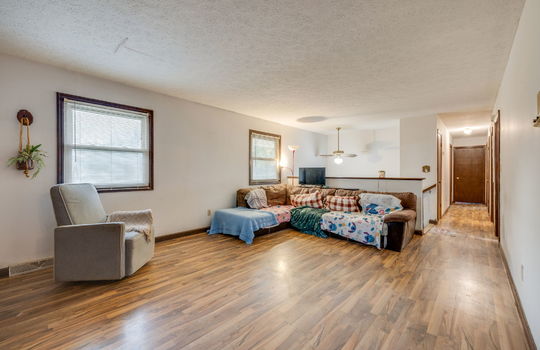 living room view toward hallway and stairs, hardwood flooring, windows, ceiling fan