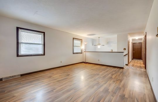 living room, furniture removed digitally, hardwood flooring, windows, ceiling fan, hallway, stairs to foyer